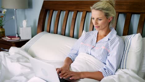 Beautiful-Blond-Woman-Working-On-Laptop-In-Bed