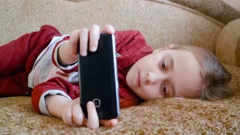 Teen-Mädchen-spielen-im-Telefon,-während-auf-der-Couch-liegen.