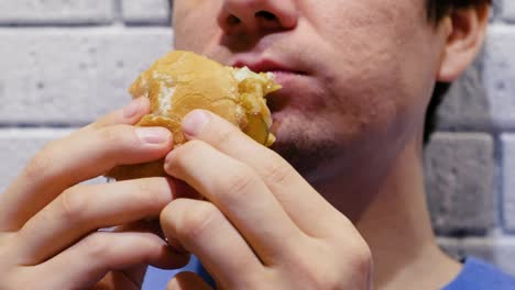 Man-is-eating-a-hamburger-with-relish-and-delight-in-cafe.