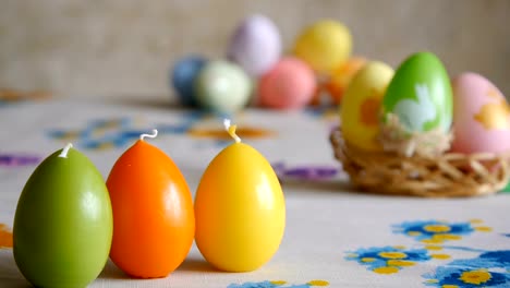 Candles-made-in-shape-of-easter-egg.-Green,-orange,-yellow.-Easter-eggs-candles-and-colorful-Easter-eggs-in-the-background.