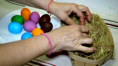 Woman-puts-colorful-Easter-eggs-in-basket-with-hay.