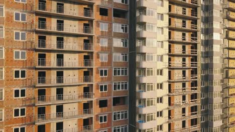 Aerial-view-of-the-facade-of-a-residential-apartment-building-under-construction.-High-rise-building-with-windows-and-balconies.-Construction-industry.-Urbanization