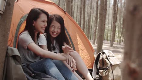 Lgbt-lesbian-women-couple-camping-or-picnic-together-in-forest,-teenager-enjoy-moment-talking-in-front-of-their-tent.-Adventure-activity-and-travel-on-holidays-vacation-in-summer.-Slow-motion-shot.