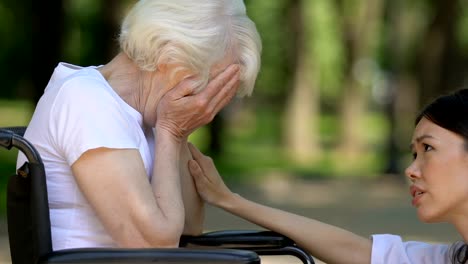 Psychologist-of-nursing-home-supporting-mature-woman-in-wheelchair,-close-up