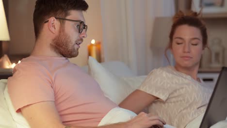 man-using-laptop-while-girlfriend-is-sleeping