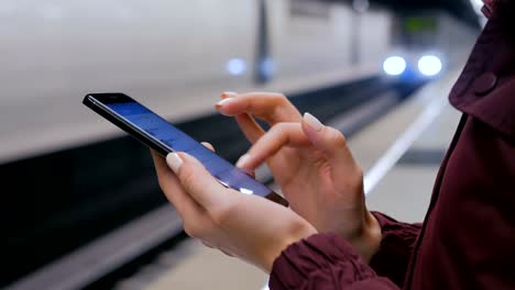 Frau-mit-Smartphone-auf-U-Bahn-Plattform