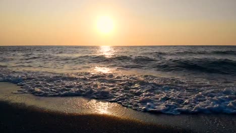 Olas-de-mar-y-una-playa-en-un-fondo-de-puesta-de-sol.