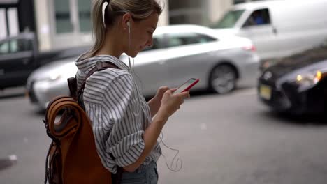 Efecto-de-cámara-lenta-de-la-chica-hipster-rubia-positiva-usando-tecnología-moderna-para-la-mensajería-al-aire-libre