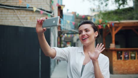 Zeitlupe-der-hübschen-Dame,-die-Selfie-draußen-mit-Smartphone-winken-Hand