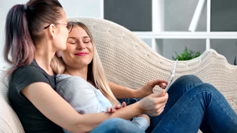 Charming-female-same-sex-couple-relaxing-together-having-tenderness-using-tablet-pc