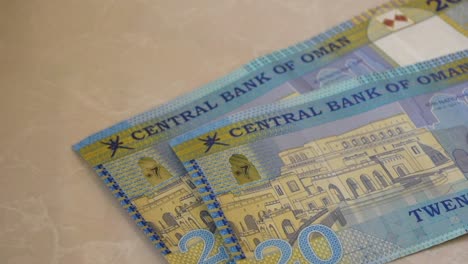 A-close-up-of-the-Central-Bank-of-Oman-20-Riyal-bills-of-cash,-the-currency-of-the-Oman-notes-spread-out-on-a-semi-white-background.-Money-exchange.