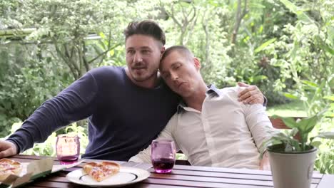 Gay-couple-having-pizza-for-lunch.-Hugging.