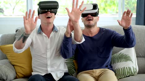 Gay-couple-relaxing-on-couch-using-virtual-reality-device.-Looking-around.