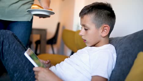 Young-boy-is-playing-games-on-his-tablet-at-home