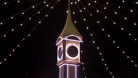 Clock-tower-decorated-with-Christmas-lights,-bulb-garlands-on-city-square-New-Year-market.-Camera-flies-around-decorative-Big-Ben-on-Christmas-Eve.-Time-and-holidays-concepts