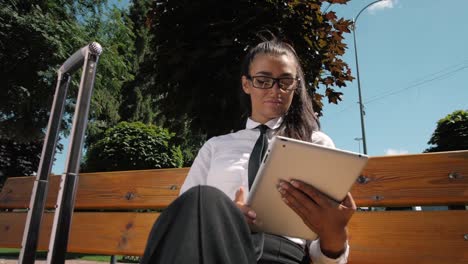 Woman-Reading-Tablet-Device.-A-young-Spanish-adult-female-latina-online-shopping-booking-outdoor-on-street,-airport-terminal