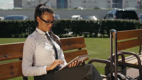 Woman-Reading-Tablet-Device.-A-young-Spanish-adult-female-latina-online-shopping-booking-outdoor-on-street,-airport-terminal