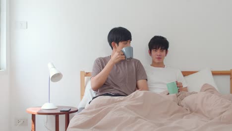 Pareja-de-hombres-gay-asiáticos-hablando-pasándose-un-buen-rato-en-casa-moderna.-Joven-Asia-amante-hombre-feliz-descanso-descanso-beber-café-después-de-despertar-mientras-se-acuesta-en-la-cama-en-la-casa-en-la-casa-en-el-concepto-de-la-mañana.