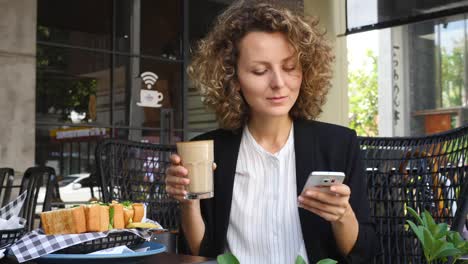 Joven-empresada-usando-smartphone-y-bebiendo-café