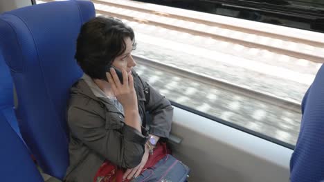 a-woman-is-sitting-on-a-train-talking-on-the-phone-side-view-from-above