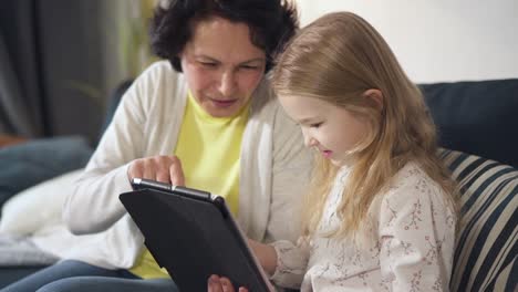 Kleine-fröhliche-attraktive-Mädchen-sitzt-und-mit-Touchscreen-Tastatur