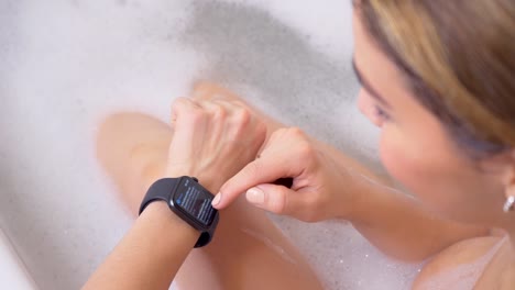 Attraktive-junge-Sportlerin-trägt-und-verwendet-Smartwatch-im-Badezimmer.-Tippen-Sie-auf-den-Bildschirm-des-Smartwatch-Geräts.