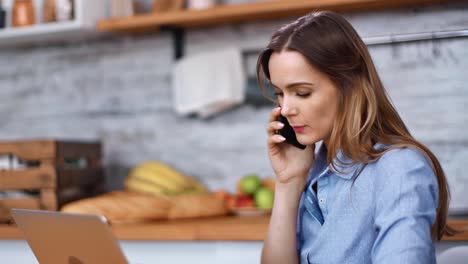 Happy-freelancer-woman-talking-smartphone-looking-at-laptop.-Medium-close-up-shot-on-4k-RED-camera