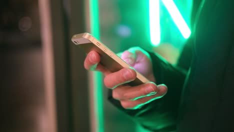 Mann-Hände-mit-Smartphone-nah-in-trendigen-Neonlichter-auf-der-Straße.-Lebensstil.-Einfaches-Bezahlen-Online-Banking-mit-Smartphone-oder-digitalem-Gerät.-Kommunikation-per-App-zum-Verkauf-im-Shop.-Social-Media