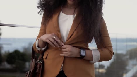 Mujer-joven-con-el-pelo-rizado-listo-para-el-blazer-de-abotonamiento-de-negocios