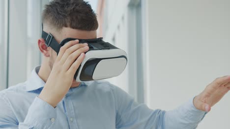 Close-up-Young-man-sitting-at-a-desk-in-the-office-uses-augmented-reality-glasses-to-work-on-business-projects-in-various-fields.-Work-in-Virtual-Reality