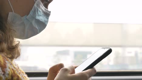 Woman-in-disposable-mask-uses-phone-in-public-transport