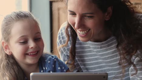 Closeup-view-mom-and-kid-having-fun-using-tablet