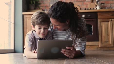 Mutter-Sohn-mit-Tablet-beobachten-Videos-lachen-dliegt-auf-dem-Boden