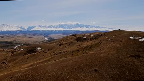 A-flight-over-a-beautiful-valley-with-snowy-mountains-in-the-distance