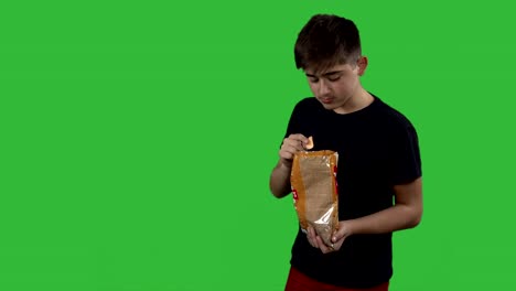 boy-eating-potato-chips-on-a-green-background.-Teen-boy-eating-junk-food