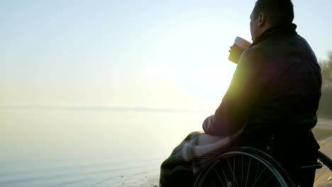 Disabled-person-in-wheelchair,-cup-of-warming-drink-in-hands-of-disabled-man