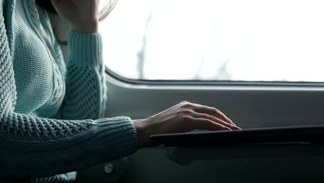 Young-girl-traveling-in-a-train-and-using-notebook.-Female-hands-using-touchpad-of-laptop-pc.-Girl-chatting-with-friends.-Close-up