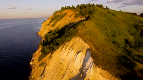 beautiful-aerial-view-of-cliff-with-trees-and-grass-on-the-river's-edge