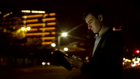 Joven-turista-está-utilizando-su-computadora-de-la-tableta-en-una-calle-en-la-noche