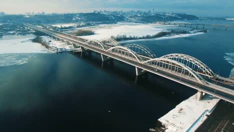 Cars-and-train-moves-on-a-bridge-over-a-frozen-river-aerial-drone-footage