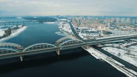 Auto-und-Zug-bewegt-sich-auf-einer-Brücke-über-einen-gefrorenen-Fluss-Luftbild-Drohne-Filmmaterial