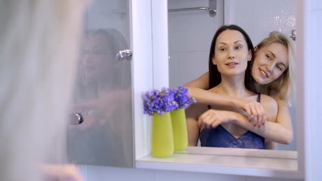 Happy-female-couple-embracing-near-the-mirror