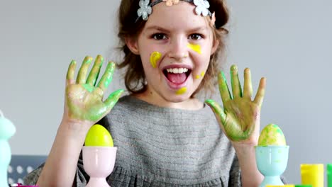 Cute-little-girl-painting-colorful-easter-eggs.-She-dirty-her-hands-and-face