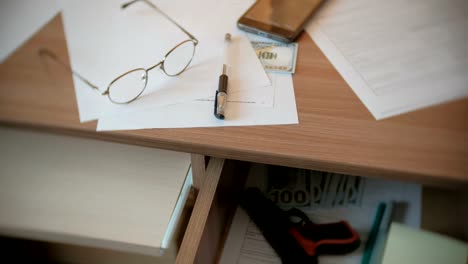 Testament,-pen,-glasses-and-money-on-the-table,-and-gun-in-a-table-drawer.