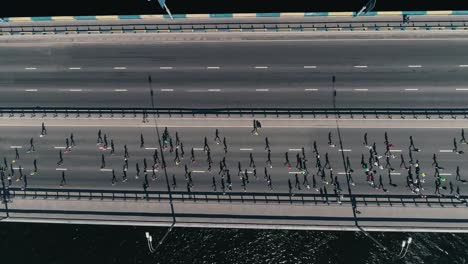 4K-Aerial-drone-fooage.-Marathon-running-on-the-bridge.-Horizontal-movement-dolly-shot-top-view