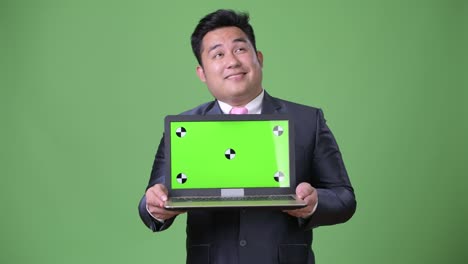 Young-handsome-overweight-Asian-businessman-against-green-background