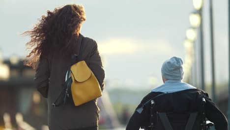 Disabled-man-in-a-wheelchair-takes-pictures-of-young-woman-at-the-quay