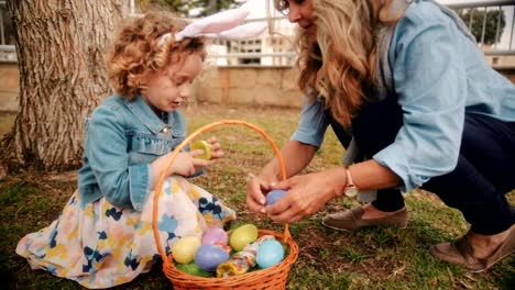 Kleines-Mädchen-mit-Großmutter-Ostereiersuche-im-Garten-genießen