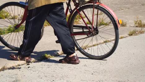 Elderly-man-walking-down-the-street-with-an-old-Bicycle