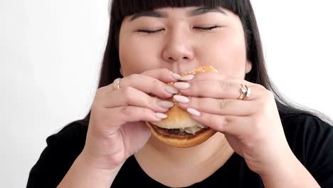 Das-Mädchen-des-asiatischen-Aussehens-einen-Burger-isst-und-genießt-den-Geschmack.-keine-gesunde-Ernährung-für-Jugendliche